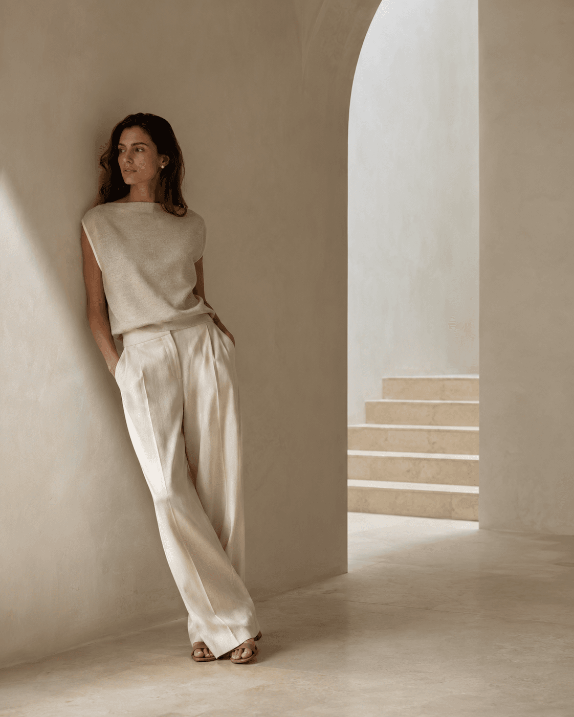 Mujer con prendas claras junto a una arquitectura minimalista